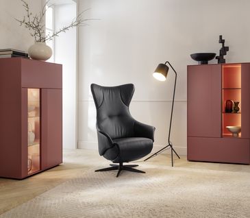 Moderner Relaxsess in schwarzem Leder in minimalistischem Wohnzimmer mit roten Highboards.