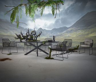 Großer, moderner Gartentisch mit sechs Gartenstühlen, gepolstert und geflochten.