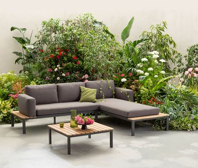 Outdoor-Loungesofa und Loungetisch vor großem Pflanzen- und Blumen-Bouquet.