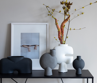 Dekoriertes Highboard mit vier verschiedenen monochromen Vasen Dekoriertes Highboard mit vier verschiedenen monochromen Vasen