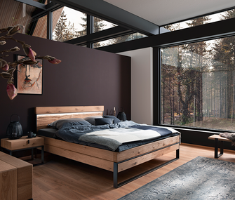 Massivholzbett vor bordeaux-farbender Wand