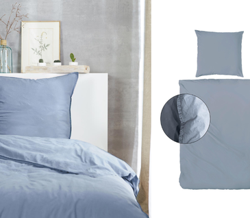 Detailbild von Bett im Schlafzimmer mit hellblauer Bettwäsche aus Baumwolle.