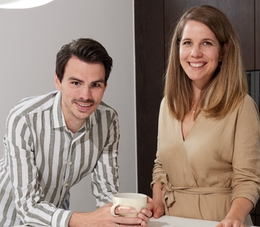 Junges Paar steht hinter Kücheninsel in ihrer neuen Küche.