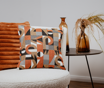 Dekokissen in rostorange auf hellem Sessel
