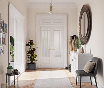 Weiße Kommode im breiten Flur auf Fischgrätenboden mit dunkelgrauem Stuhl und vielen Pflanzen