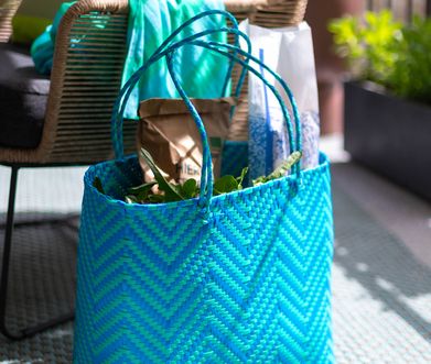 Blaue Tasche steht neben Gartenstuhl auf einem Balkon.