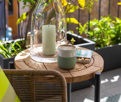 Beistelltisch auf Balkon mit einer Tass Kaffee und einer Kerze dekoriert.