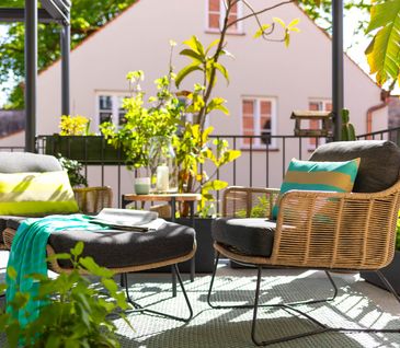 Gepolsterter Gartenstuhl mit passendem Fußteil auf sonnigem Balkon.