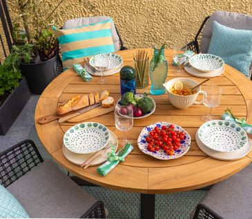Runder Gartentisch mit Teak-Holz-Tischplatte und vier Gartenstühlen.