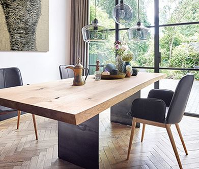 Massivholztisch aus Nussbaum neben schwarzen und modernen Lederstühlen