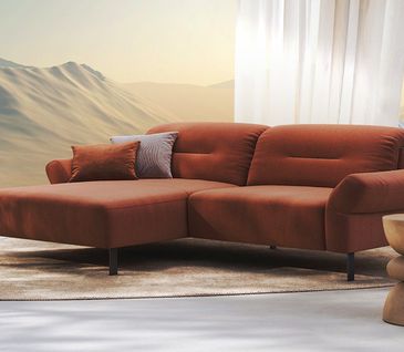 Terrakottafarbenes Ecksofa in Studioatmosphäre mit Vorhang und Dünen im Hintergrund