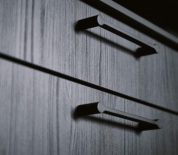 Die Details machen das Design - auch bei den Küchen von Homepoet! Ausschnitt eines schwarzen Holz-Küchenunterschranks mit einem schwarzen Metall-Bügelgriff