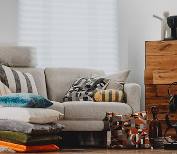 Beiges Sofa dekoriert mit vielen Kissen und Wohndecken