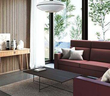 Dunkelrotes, frisch gereinigtes Ecksofa im Wohnzimmer mit großen Fenstern vor schwarzem Couchtisch