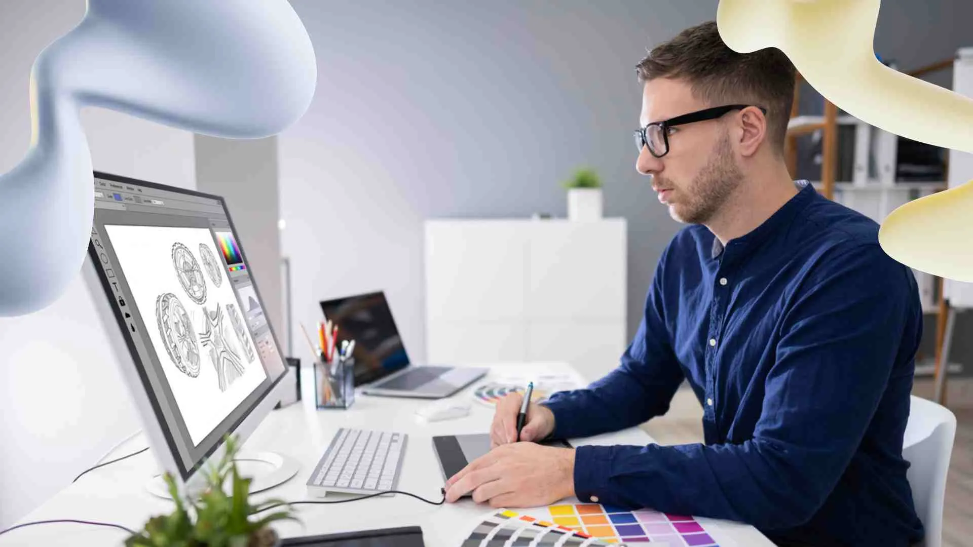 A man in glasses uses a graphics tablet to design intricate coin-like graphics on a computer monitor in a modern office.