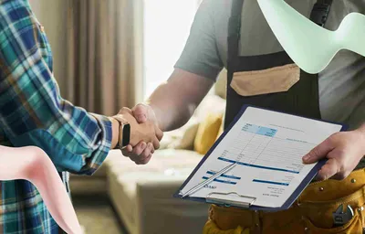 Technician with tool belt and invoice shakes hands with a customer. A green energy symbol suggests electrical services.
