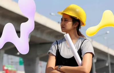 Young woman in yellow hard hat holding rolled plans, looking thoughtfully at a construction site with concrete overpasses and graphic shapes.