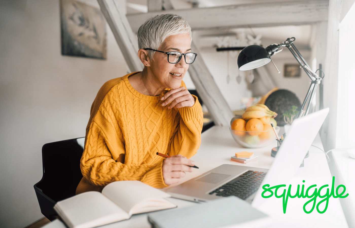 A white-haired woman in an orange jumper is sat at a laptop, pen in hand. The word 'squiggle' is in green letters.