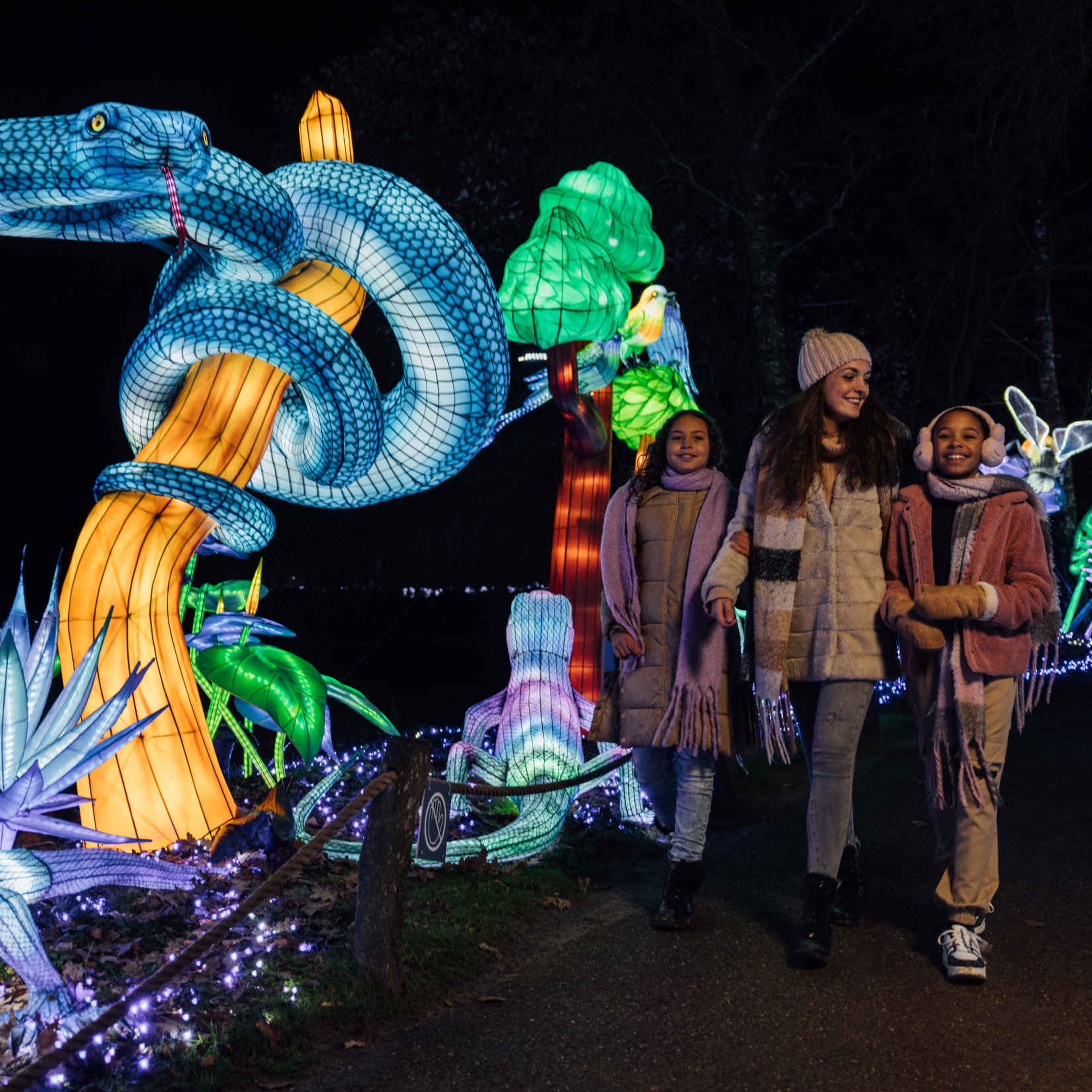 Moeder met twee kinderen en slang bloemen bomen tijdens Light Safari in Safaripark Beekse Bergen