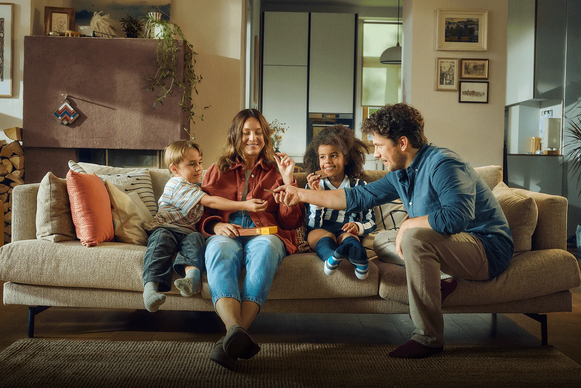 Familie sitzt auf dem Sofa und genießt zusammen LEIBNIZ Choco Kekse