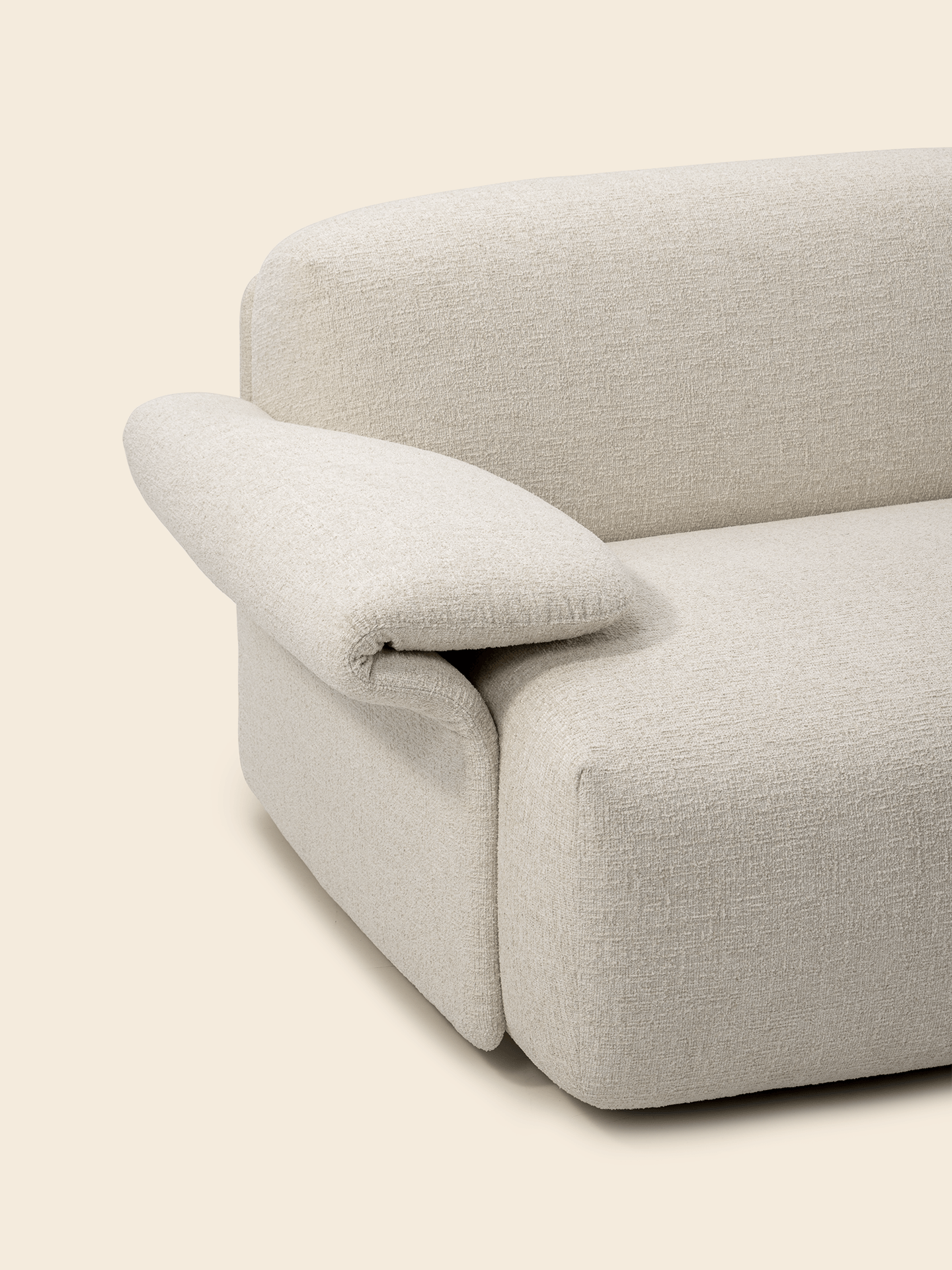 Close-up of a beige, textured sofa with a modern, curved design and adjustable armrest against a neutral background.