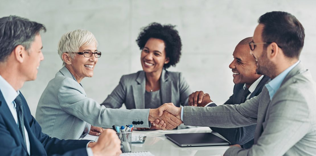 Geschäftsfrau und Geschäftsmann schütteln sich die Hand über den Tisch