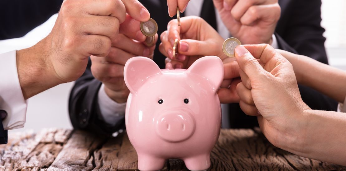 Menschen werfen Geld ins Sparschwein