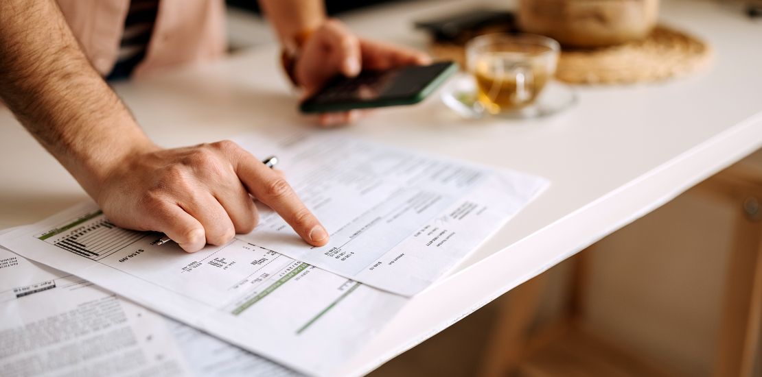 Mann mit Taschenrechner am Telefon und Rechnungen