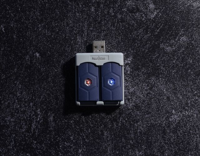 FightCamp Trackers on their charger, glowing red and blue hexagonal lights, placed on a textured dark surface.