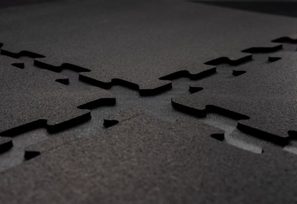 Close-up of interlocking black mats with textured surfaces, forming a seamless connection.
