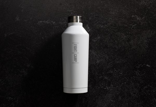 A white insulated water bottle with "FIGHT CAMP" text stands upright against a dark, textured background.