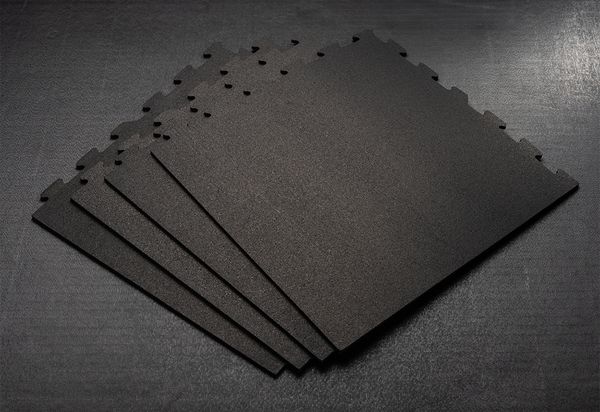 Five black, textured blocks with interlocking edges are fanned out on a dark surface.