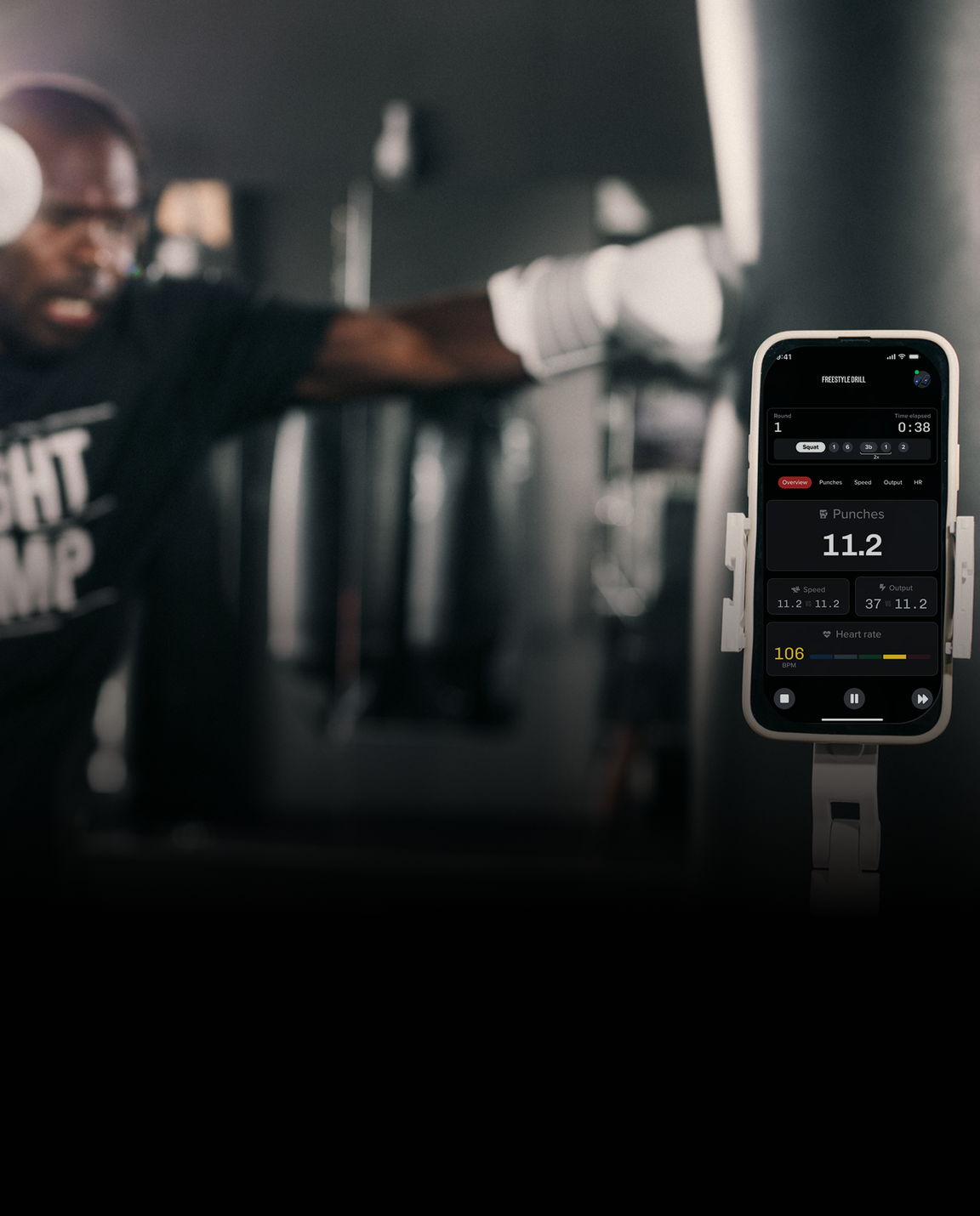 A person training with gloves at a gym, punching a bag, while a smartphone records data about the workout, including punch count and heart rate.