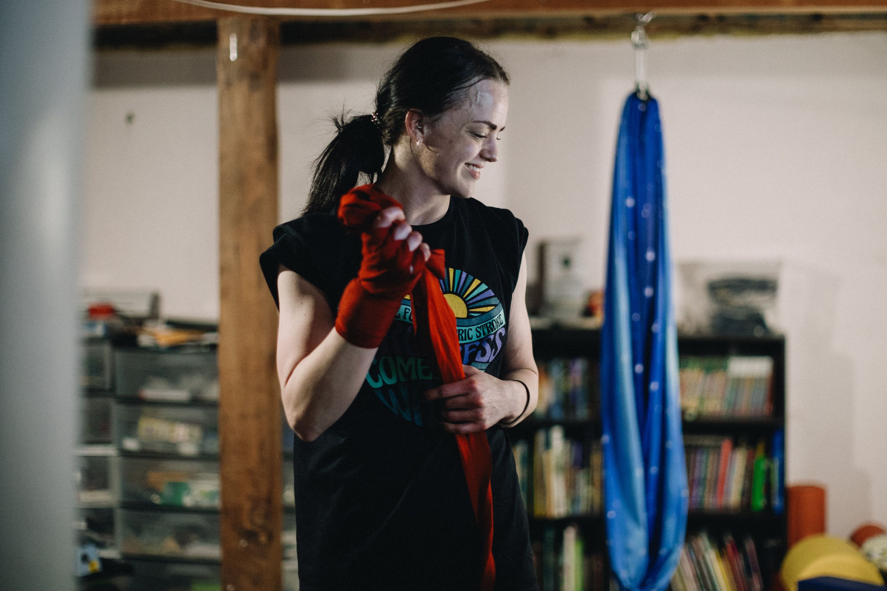 Person wrapping hands with red traditional wraps, standing in home boxing gym