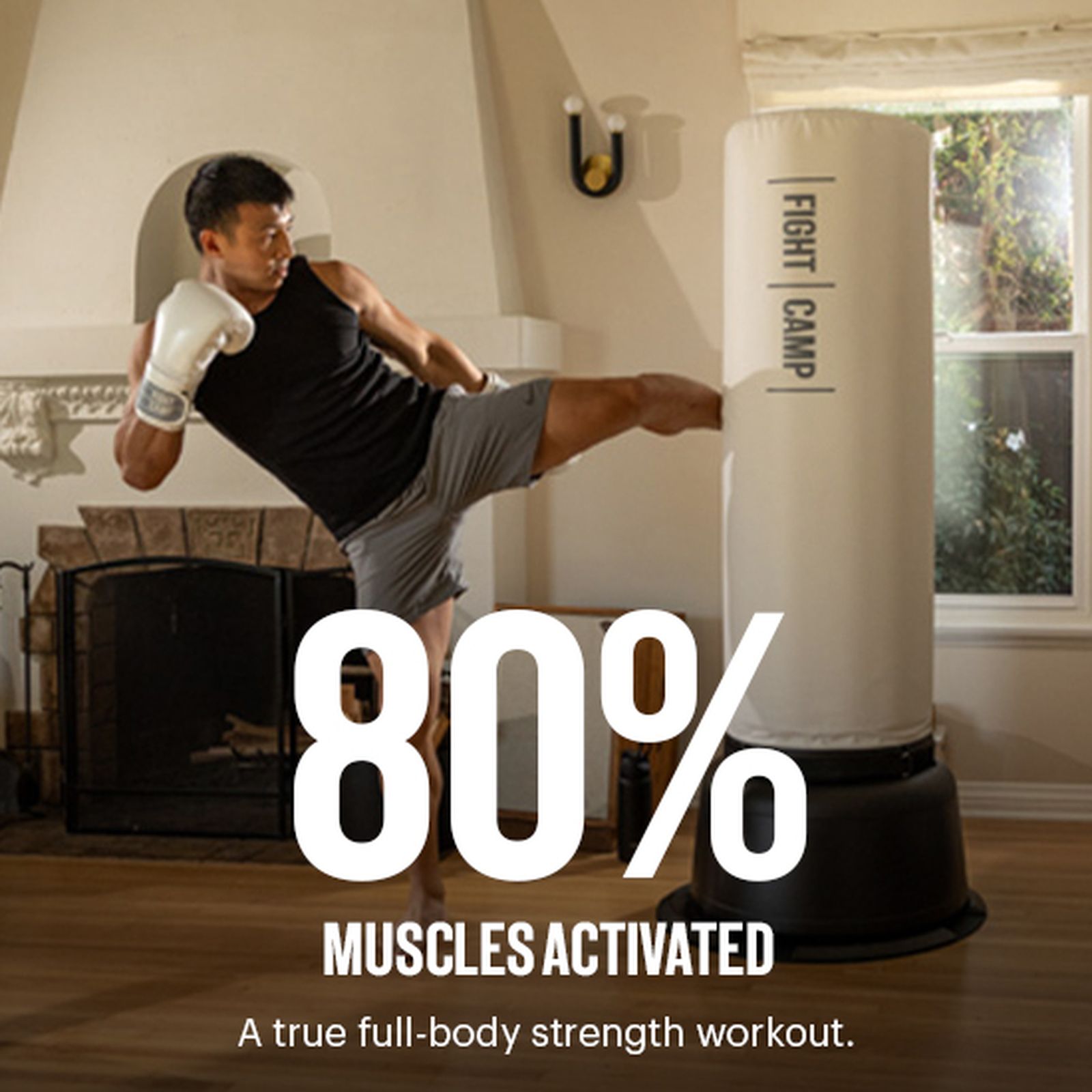 Person in workout attire kicking a punching bag in a living room, text reads "80% Muscles Activated - A true full-body strength workout."