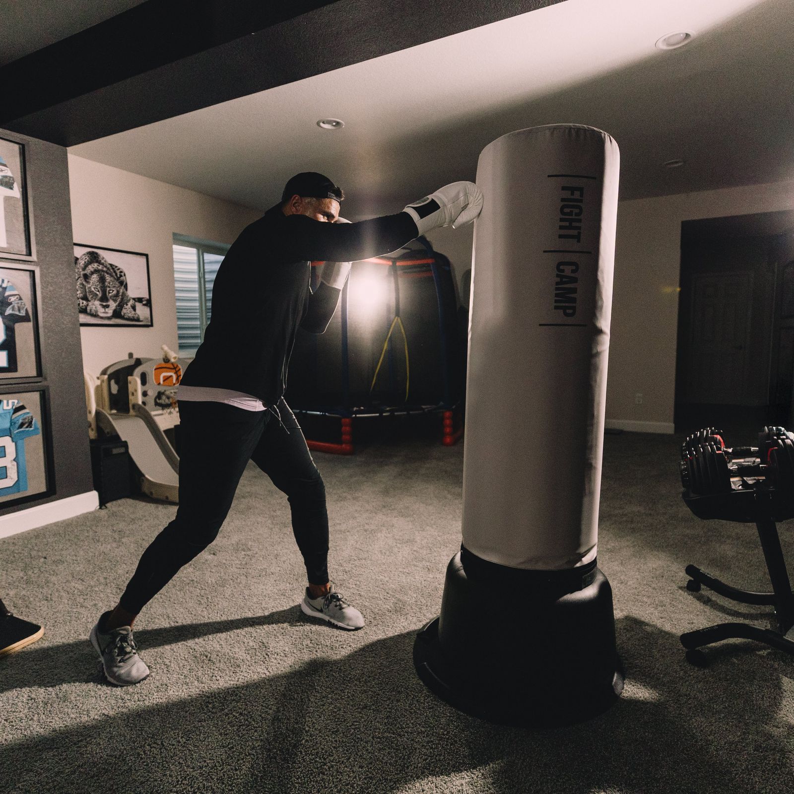 FightCamp user taking boxing class in home gym, FightCamp workout playing on tv