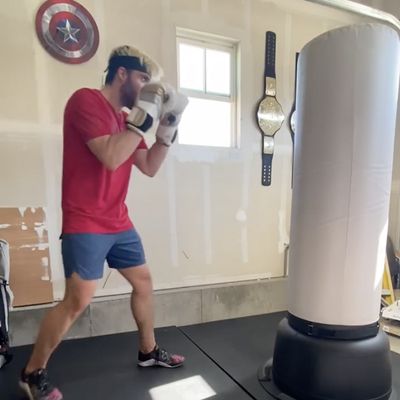 Man in boxing stance in front of FightCamp bag in garage