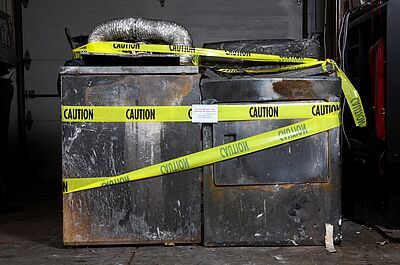 A washer and dryer brunt to a crisp with caution tape around it.