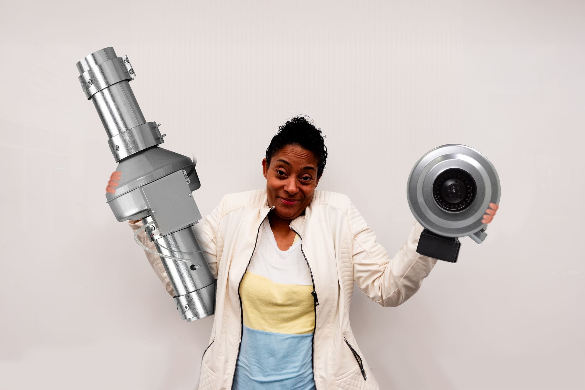 Woman shrugging holding up a DEDPV in one hand and an inline fan in the other hand