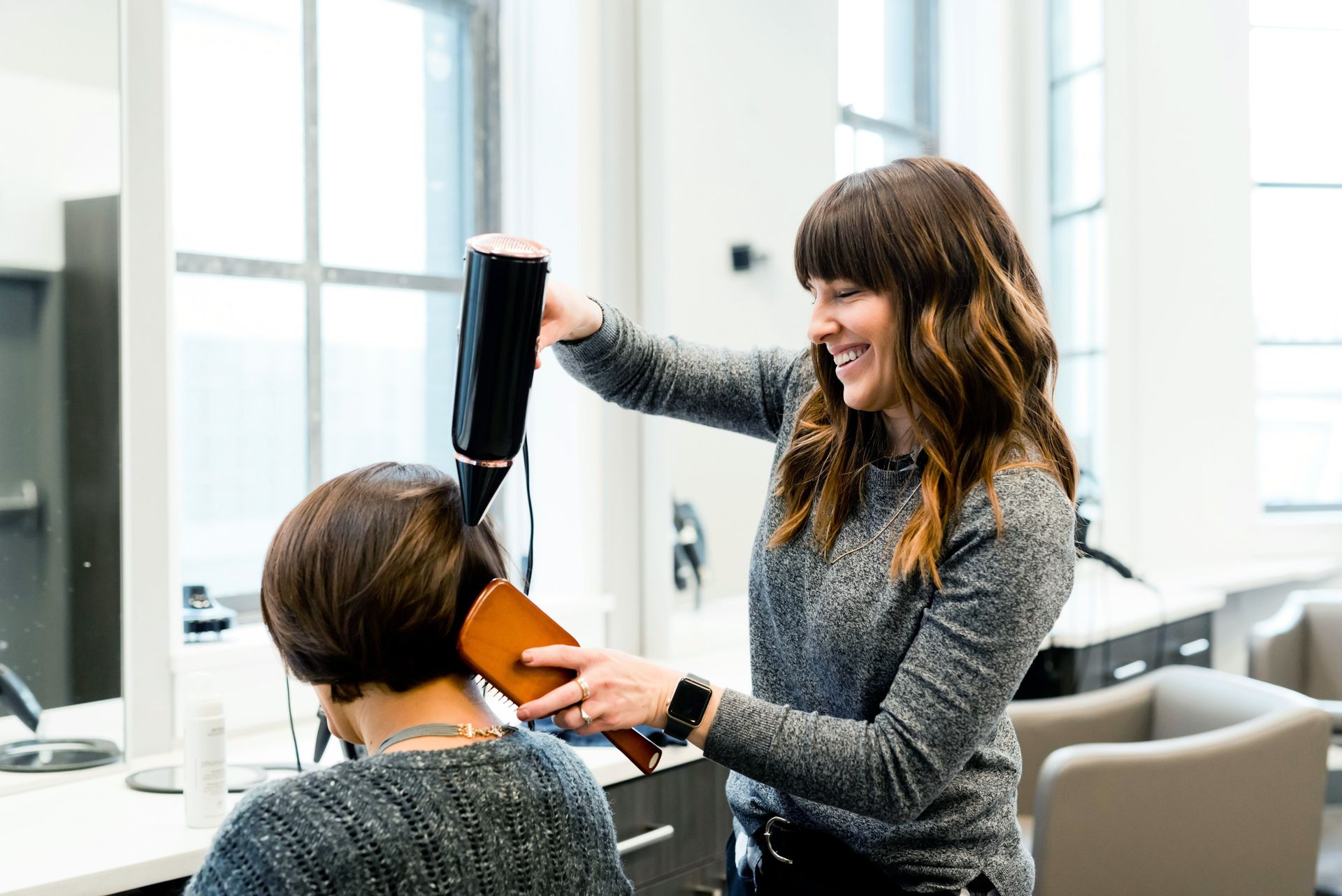Picture of woman blow drying and brushing another woman's hair at a salon