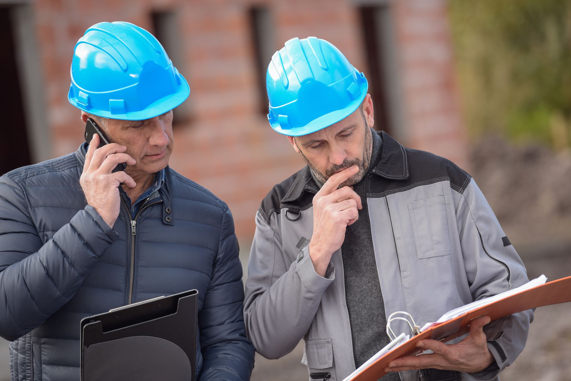 Two people in hard hats looking a binder