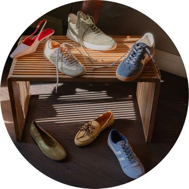 A wooden bench displays assorted shoes, including sneakers, loafers, and high heels, with more shoes scattered on the floor below.