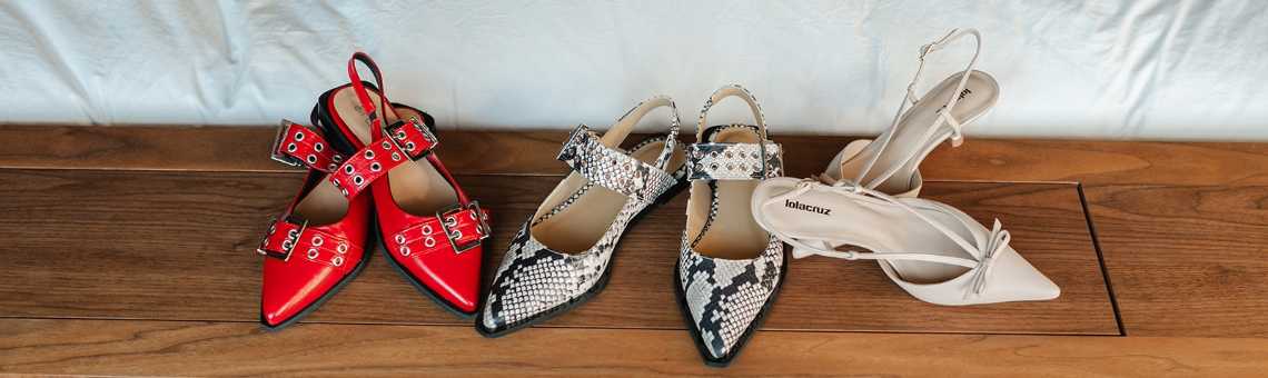 Platte rode slingback ballerina's met studs, platte slingback ballerina's met panterprint en nudekleurige slingbacks met hak op houten ondergrond