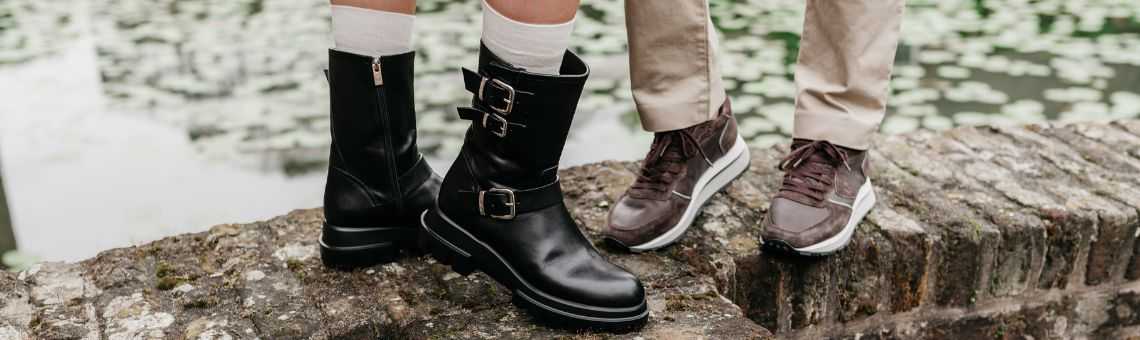 man en vrouw poseren op een muurtje. de vrouw heeft winterlaarzen aan en de man sneakers