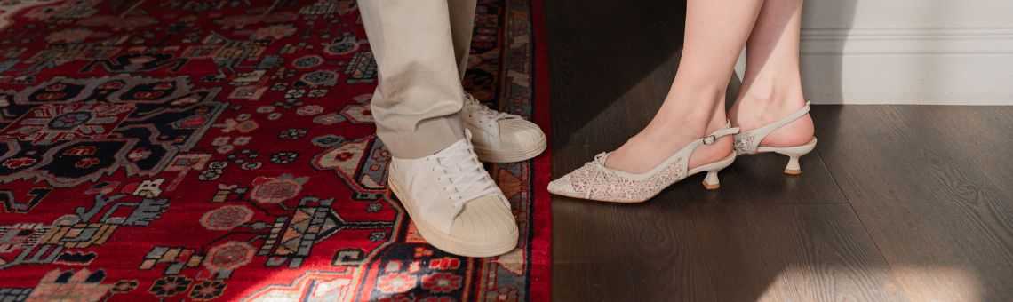 Dames schoenen en herensneakers op een rood ttapijt poseren voor de camera waarbij alleen schoenen te zien zijn