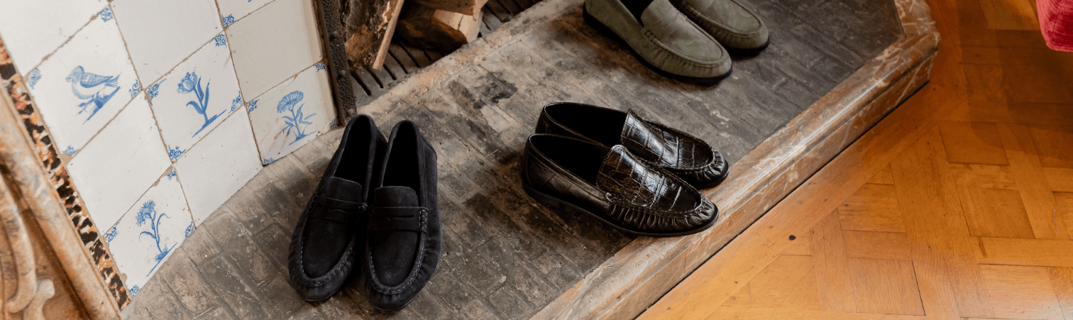 Drie verschillende heren loafers op schouw met gebakken klinkers en delftsblauwe tegeltjes