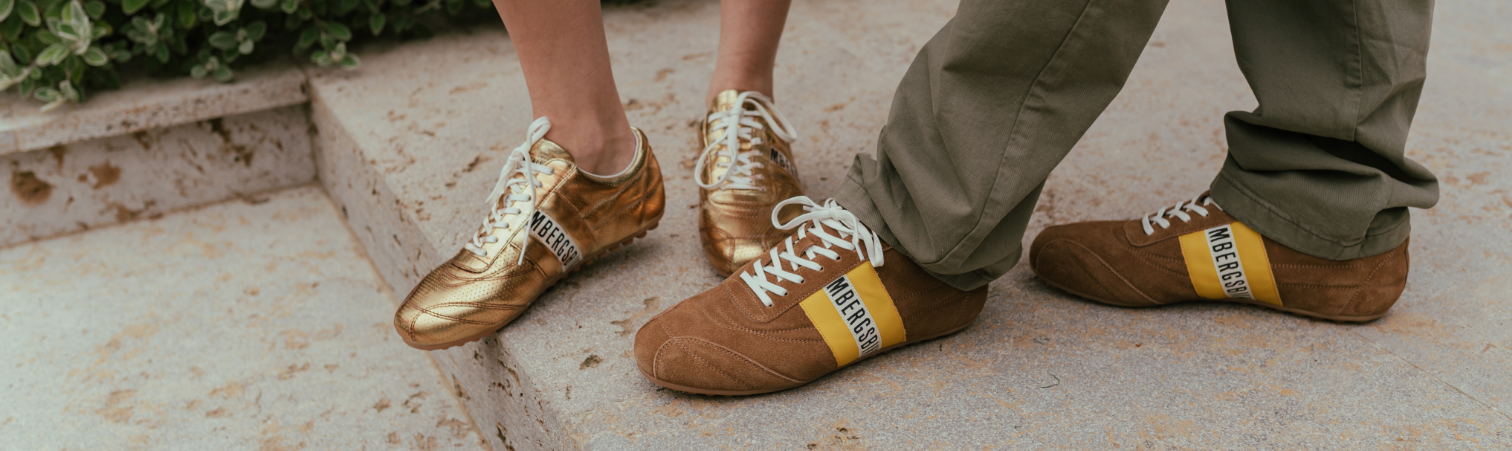 Gouden en bruine low-profile sneakers op stenen ondergrond