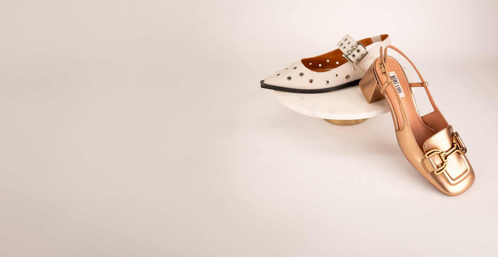 Studiobeeld van twee verschillende slingback schoenen op marmeren plateau