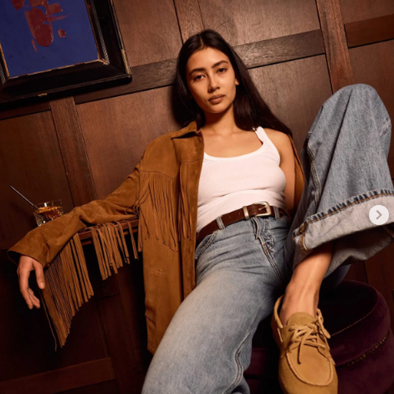 model met ruffle jack en suede bootschoenen op een stoel