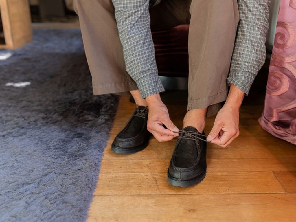 Close-up mannenhanden die veters van donkerbruine veterschoenen aantrekken